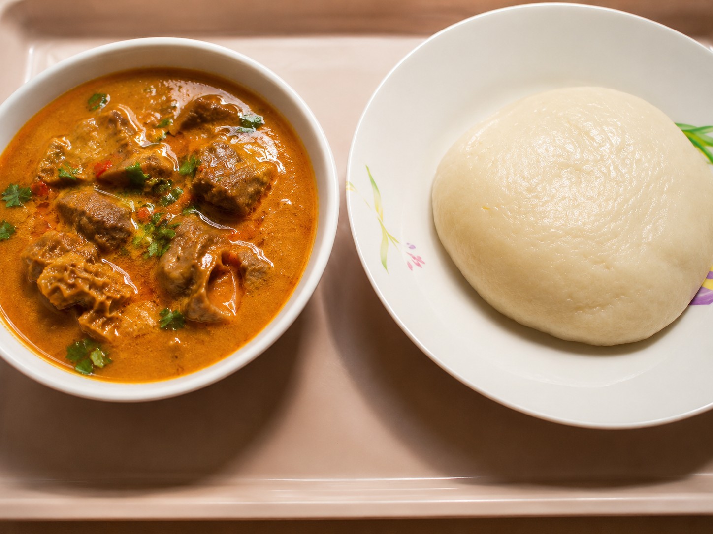 Tre runde, tradisjonelle afrikanske fufu kuler servert i en hvit skål på godtnoe.no