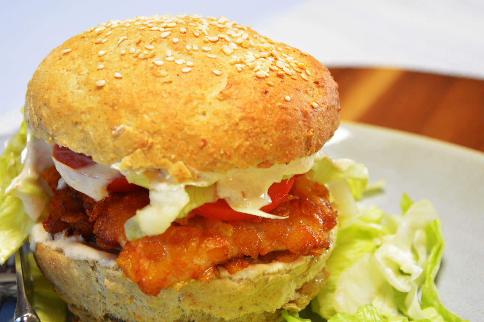 Crispy kyllingburger med sprø panert kylling, tomat, salat og chilimajones i et sesamdrysset burgerbrød