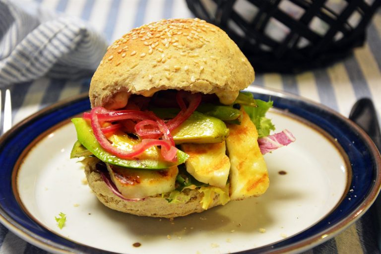 Halloumiburger i sesambrød med grillstekte halloumiskiver, avokado, syltet rødløk og salat på en tallerken