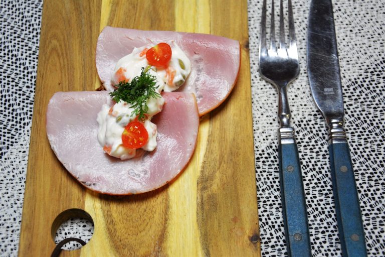 Italiensk salat med gulrotterninger og erter på to brettede skiver kokt skinke på grovbrød, pyntet med en halv cherrytomat og dill