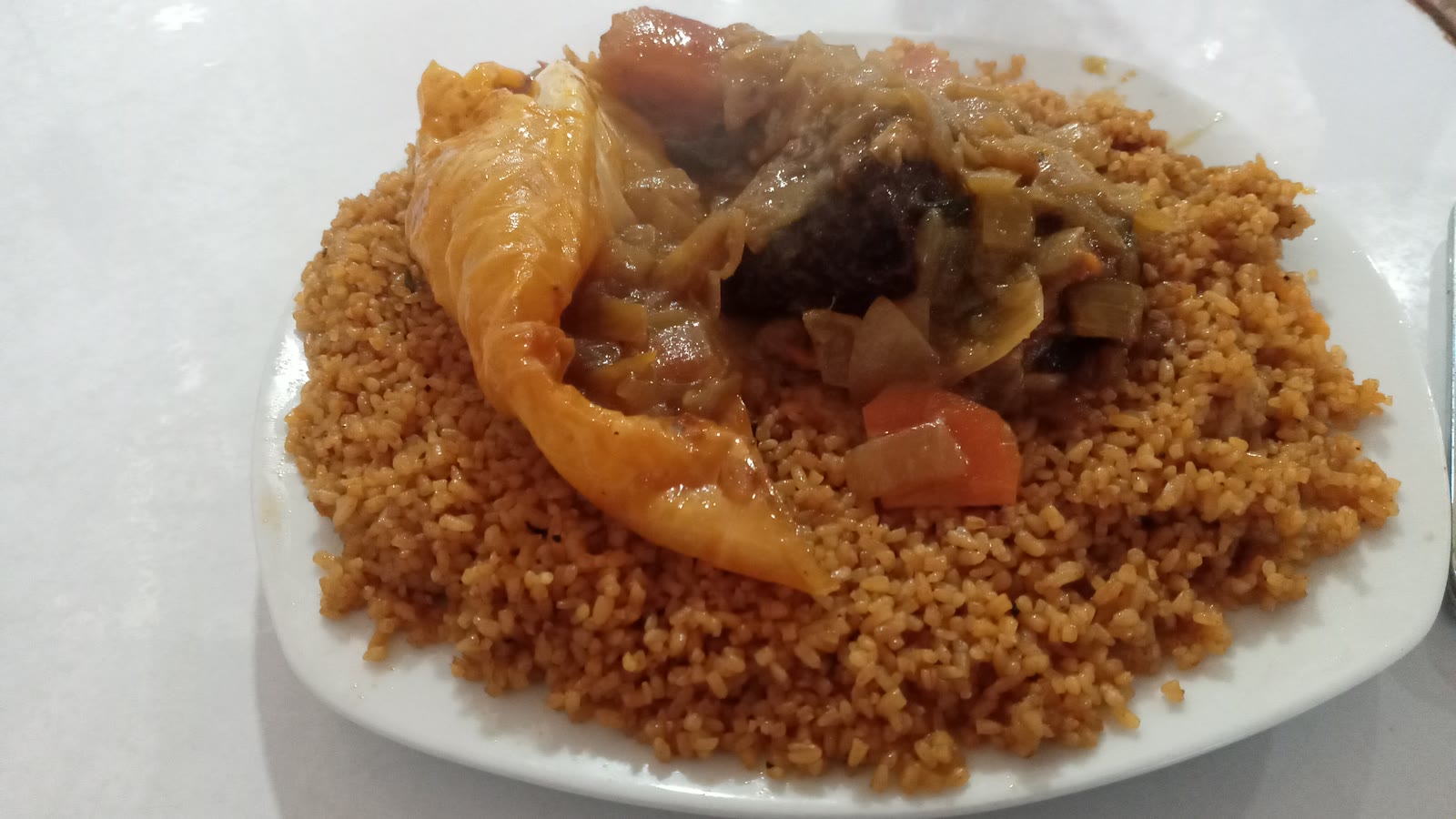 Senegalsk jollof-ris med fisk, kål og grønnsaker på en hvit tallerken