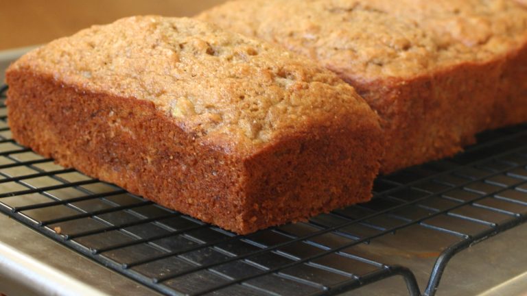 To nybakte bananbrød med gyllen skorpe avkjøles på en kakerist – oppskrift på bananbrød på godtnoe.no